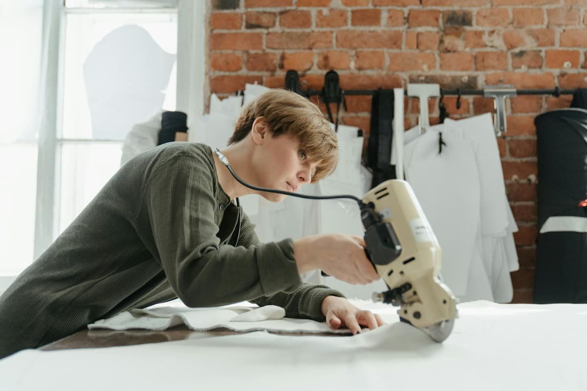 Woman in Gray Long Sleeve Shirt Holding White and Black Electric Sewing Machine
